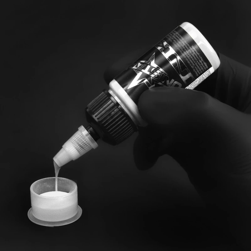 Unistar Top Basic White Tattoofarbe wird mit Handschuh in eine Farbkappe gefüllt