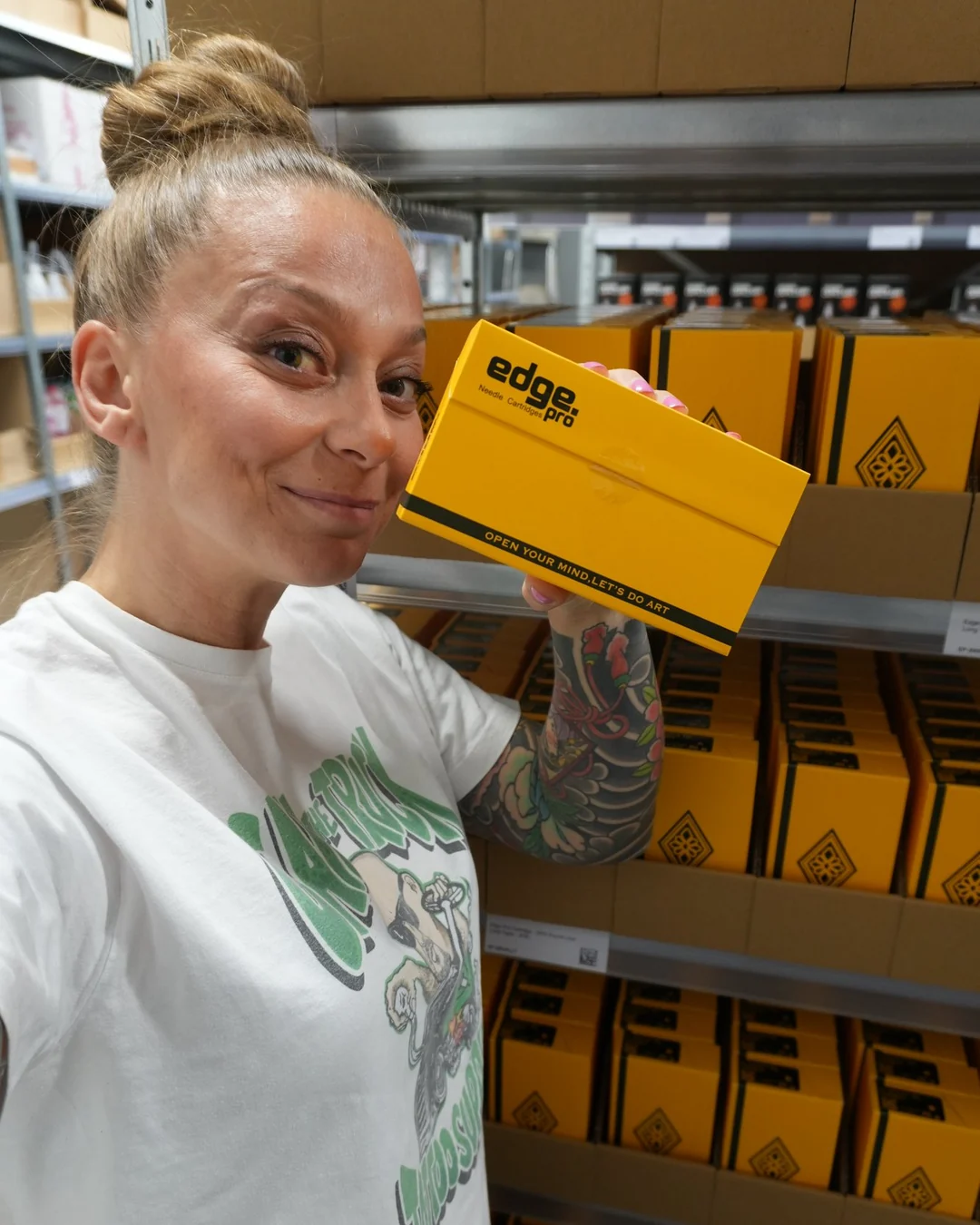 Tina steht im Lager von Call The Truck in Schwerte vor Regalen mit Edge Pro Cartridges und h&auml;lt einen Karton hoch