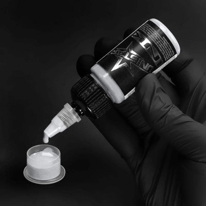 Unistar Basic Gray Ultra Light Tattoofarbe wird mit Handschuh in eine Farbkappe gefüllt