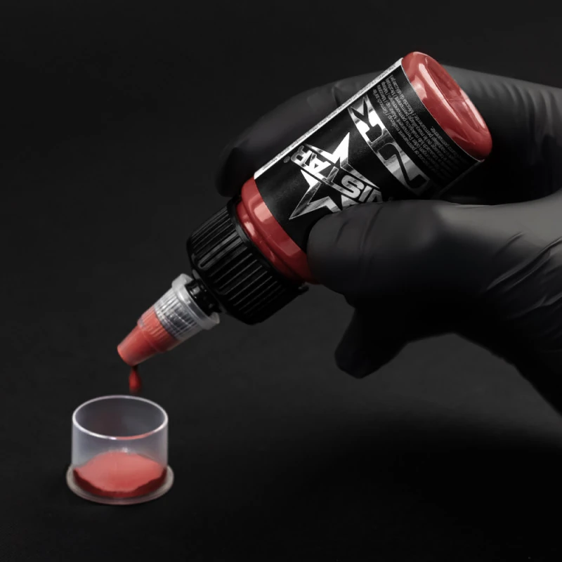Unistar Ruby Tattoofarbe wird mit Handschuh in eine Farbkappe gefüllt