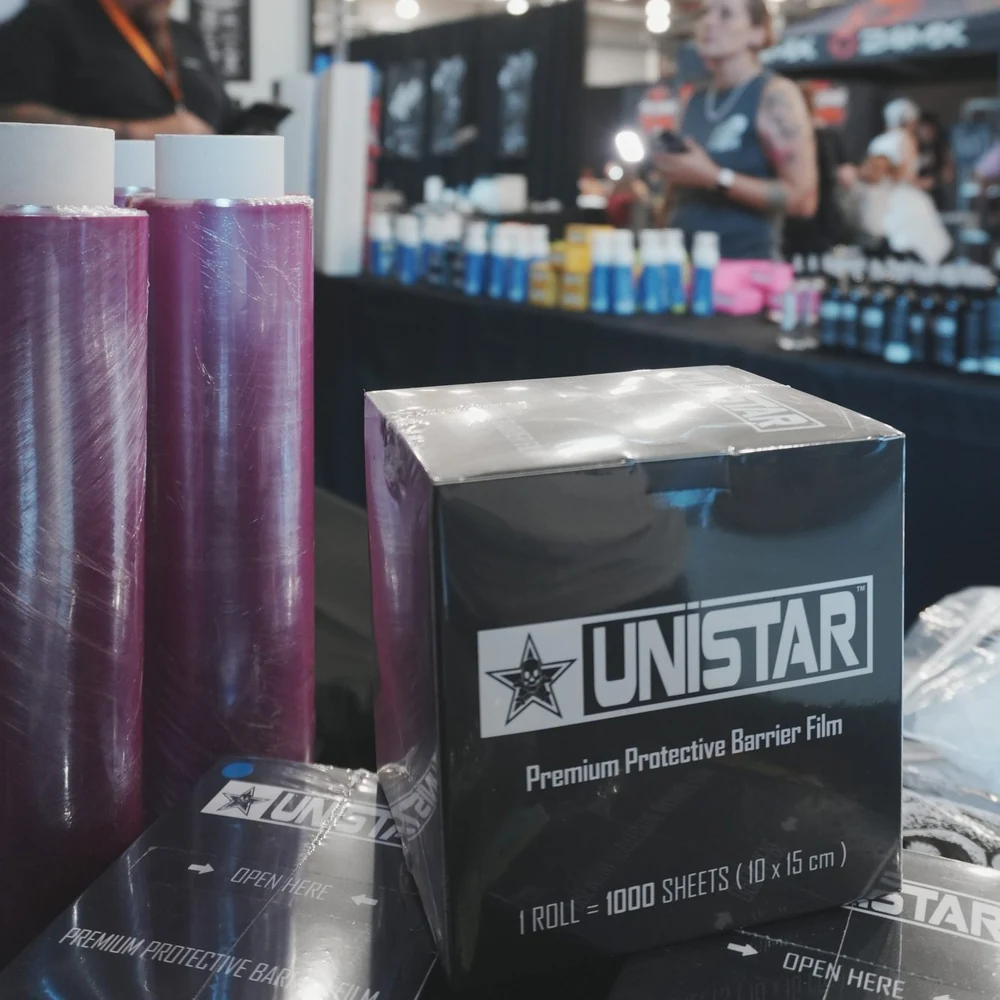 Unistar Premium Protective Barrier Film, Schachtel mit dem Hinweis eine Rolle gleich 1000 Blatt, daneben Folienrollen auf einem Messestand