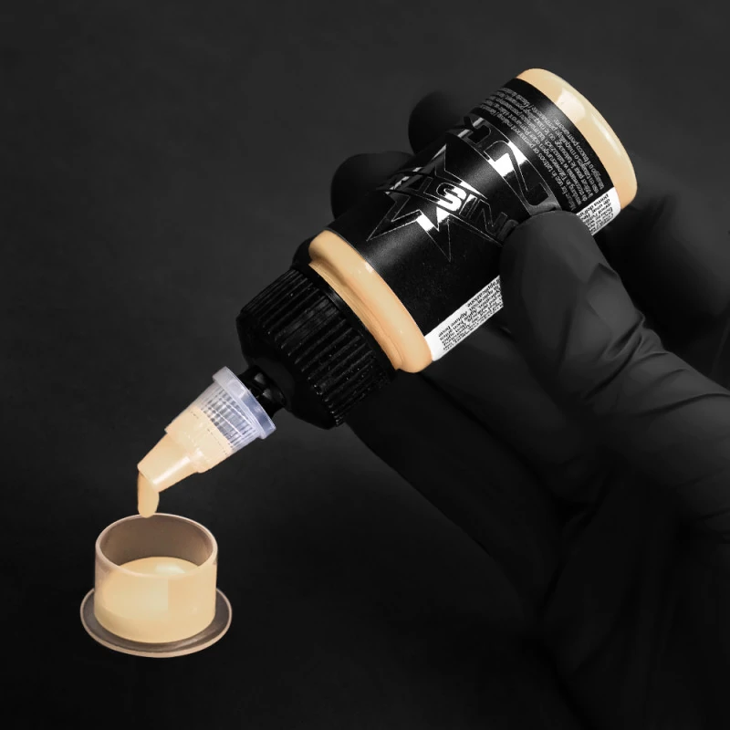 Unistar Tan Tattoofarbe wird mit Handschuh in eine Farbkappe gefüllt