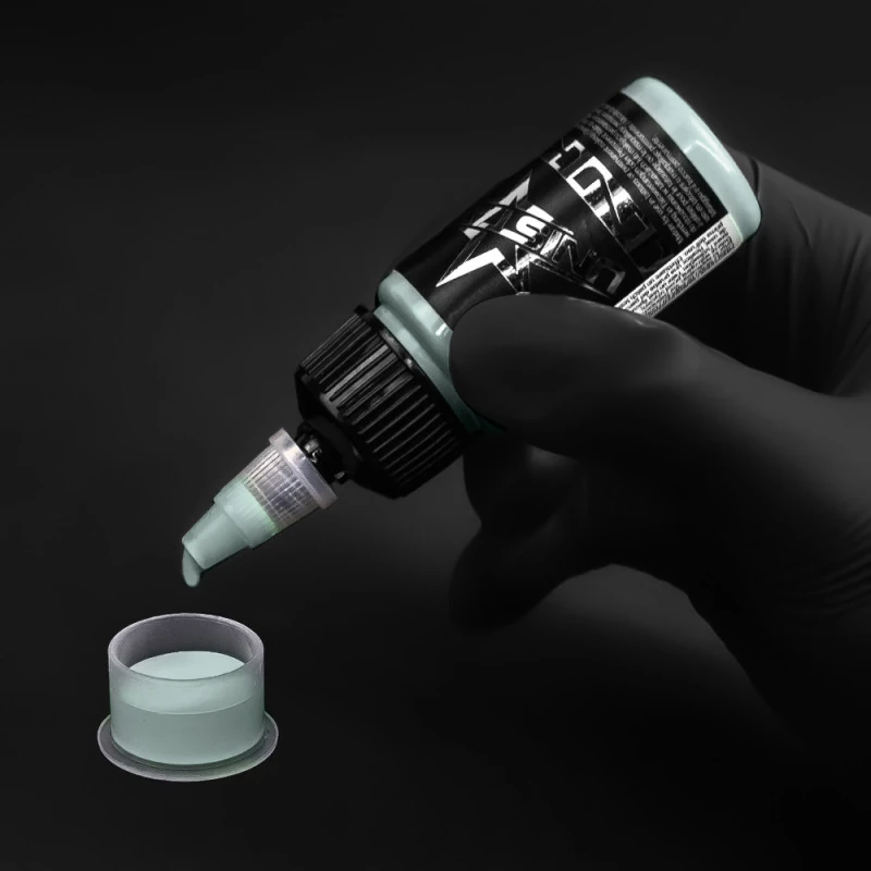 Unistar Celadon Green Tattoofarbe wird mit Handschuh in eine Farbkappe gefüllt