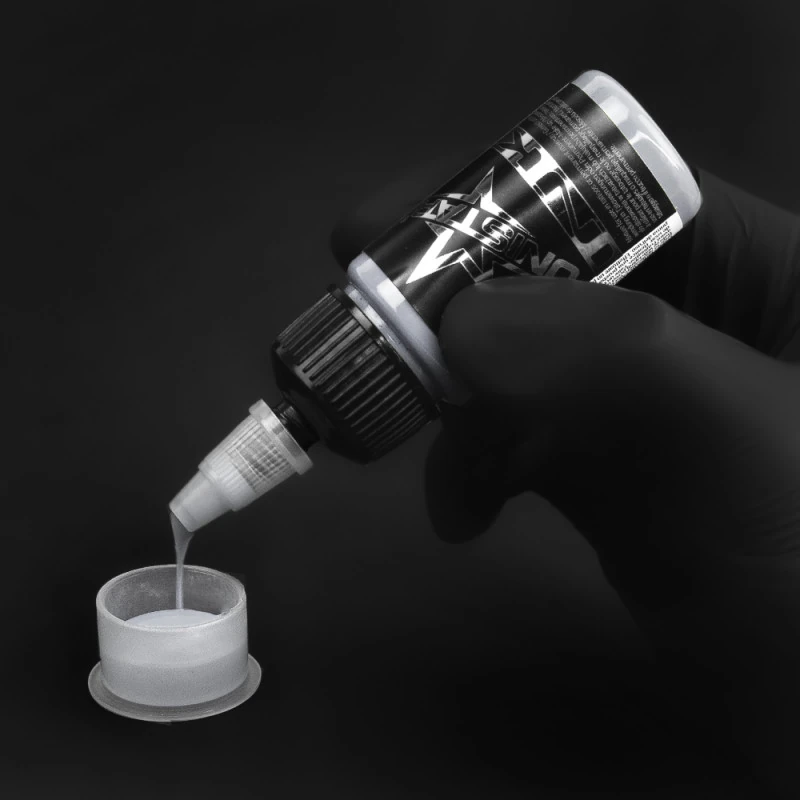 Unistar Basic Gray Light Tattoofarbe wird mit Handschuh in eine Farbkappe gefüllt